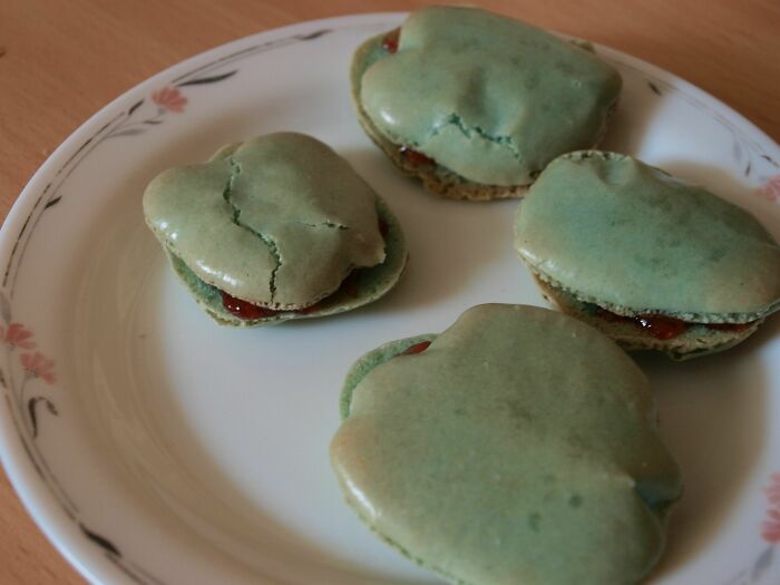 Failed DIY baking attempt with c*****d green macarons on a white floral plate, showcasing a clear DIY fail.