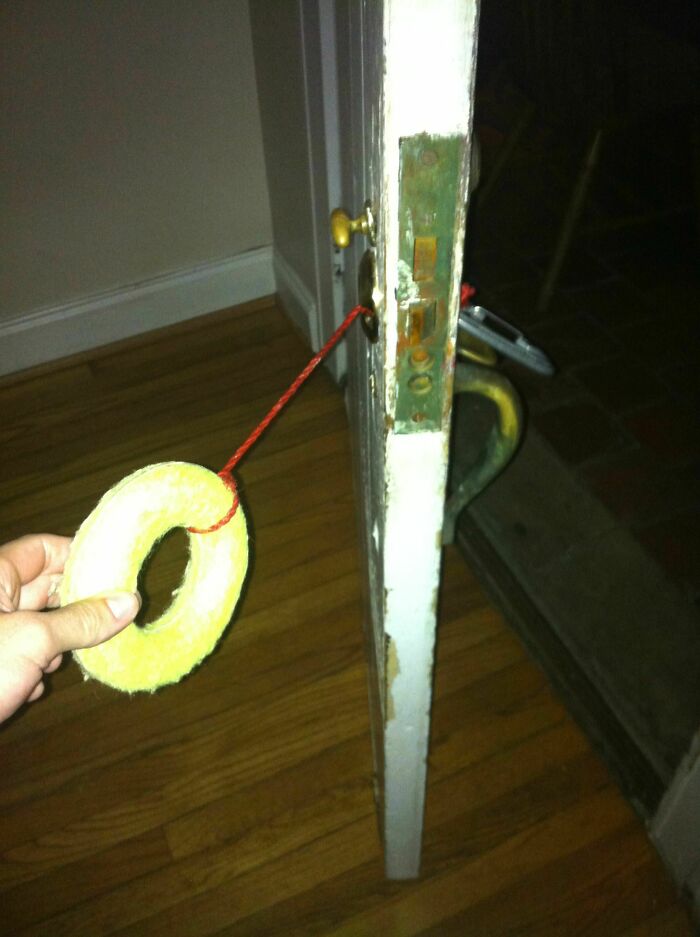 Person holding a makeshift door lock using a string and a round object showing a DIY fail needing shaming.