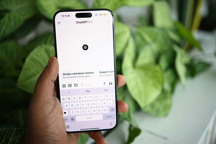 Person holding smartphone with ChatGPT open, using AI as a personal relationship coach in a casual setting.