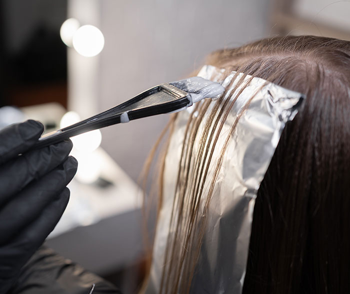 Hair coloring process with foil wraps in a salon highlighting techniques used by a professional stylist discussing Trump&rsquo;s hair changes.