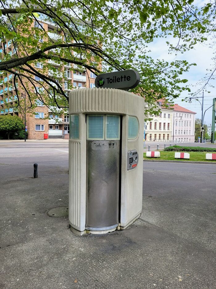 Public toilet booth in a European city showing normal practices US may find weird in urban street setting.