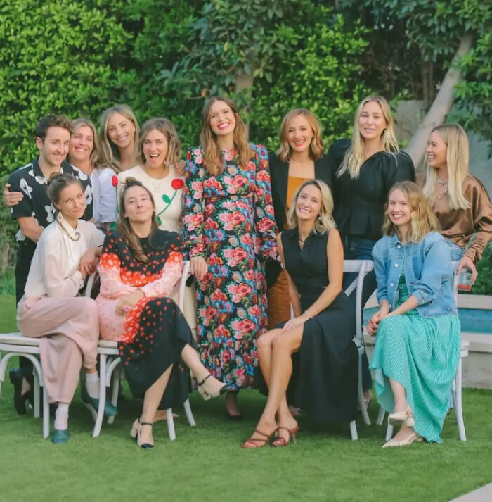 Ashley Tisdale in floral dress standing with smiling group of celebrity moms at a backyard gathering