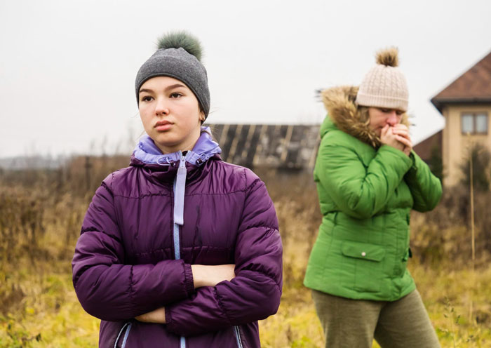 Teenage daughter looking upset with arms crossed outdoors as parents treat daughter as family when labor is needed and business when money's involved. Teenage daughter looking upset with arms crossed outdoors as parents treat daughter as family when labor is needed and business when money's involved.