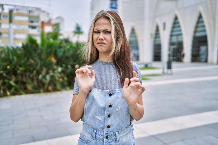 Young woman looking uncomfortable and hesitant outdoors, expressing child-loathing and refusal to be a free nanny.