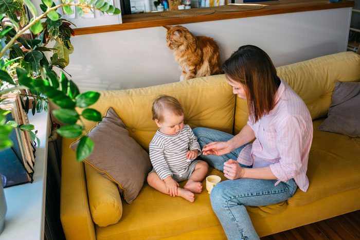 Woman with child on yellow sofa, illustrating child-loathing lady caring for toddler in a family home setting.