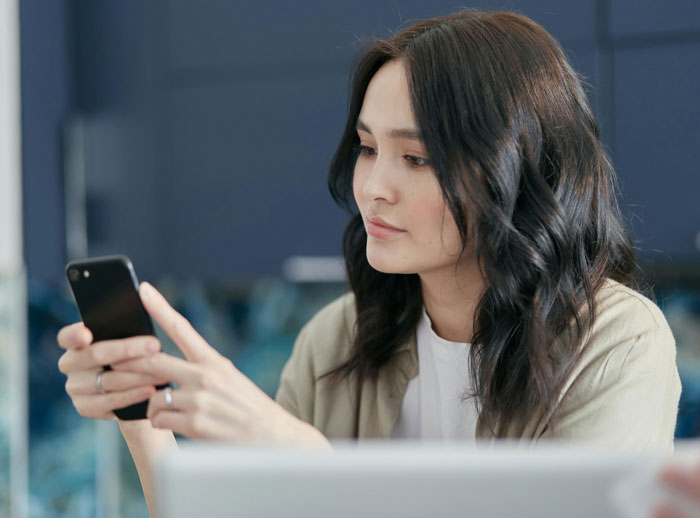 Woman using smartphone looking concerned, illustrating a casual boyfriend with a piece on the side in a 3-year situationship.