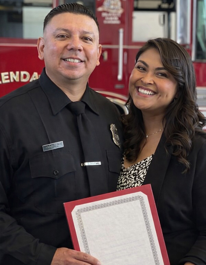Smiling couple posing indoors, woman holding a framed document, highlighted by teacher&rsquo;s life affair diary discovery keywords.