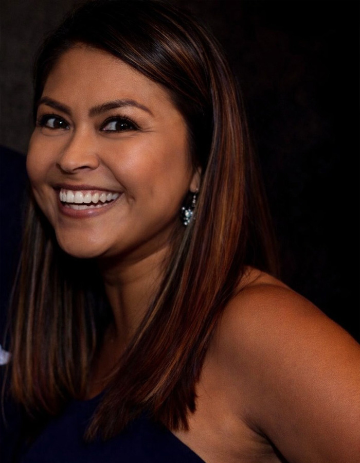 Smiling woman with brown hair and earrings in a dark setting illustrating teacher&rsquo;s life ends after diary affair discovery.