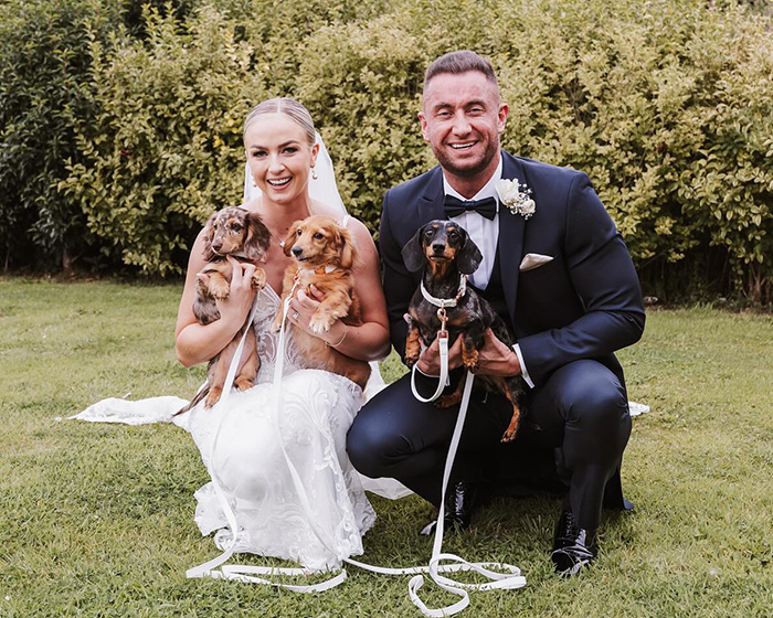 Bride and groom on wedding day holding three small dogs, capturing a joyful moment despite tragic loss keyword anniversary.