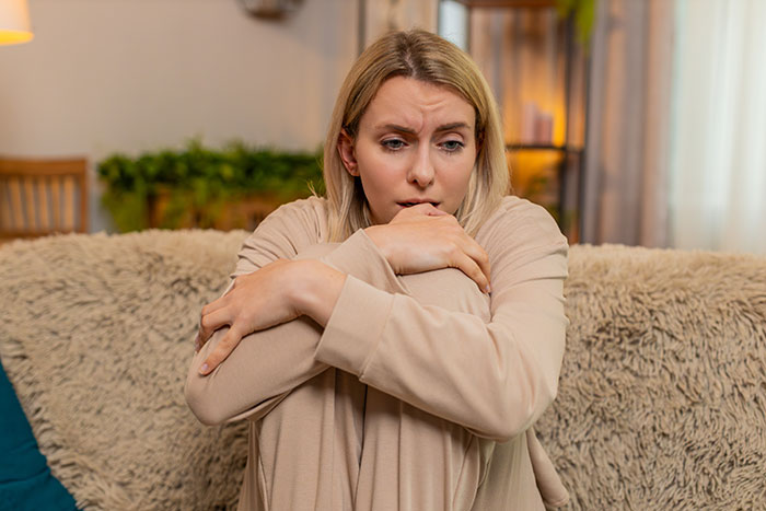 Woman looking worried sitting on sofa, reflecting trust and emotions about husband leaving without jealousy