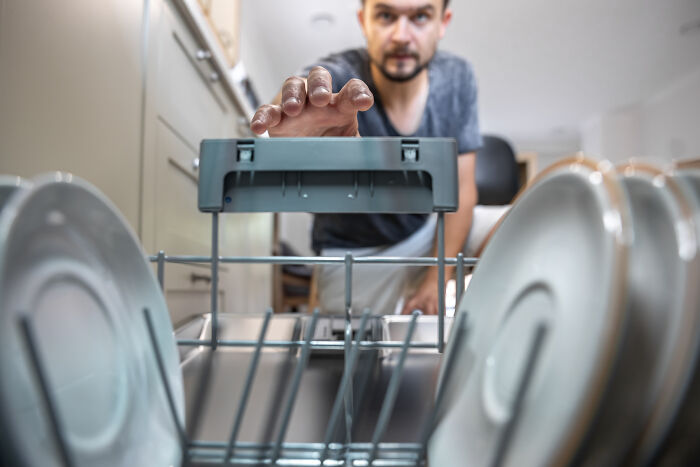 Man loading dishwasher in kitchen, illustrating hygiene anxiety and OCD-like cleaning behavior in family setting.