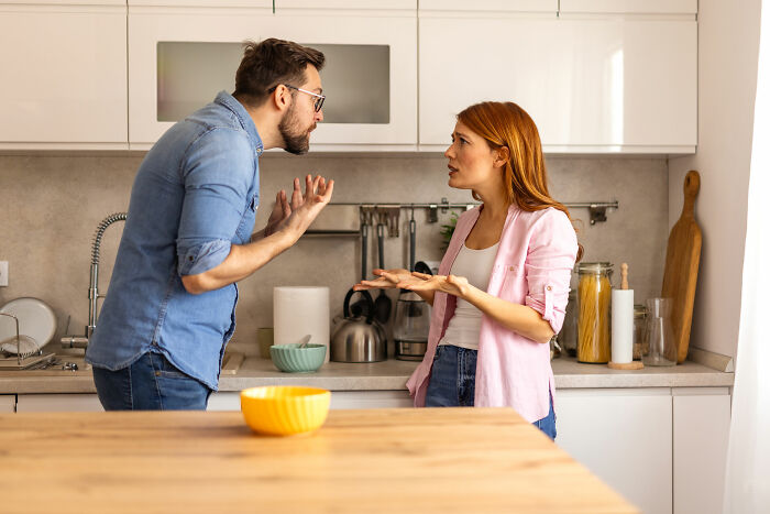 Couple in a kitchen having a heated argument, illustrating mom with OCD-like hygiene anxiety causing family tension.