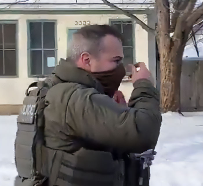 ICE officer in tactical gear outside a house in Minneapolis near the site involving a mom of a 6-year-old slain in her car.