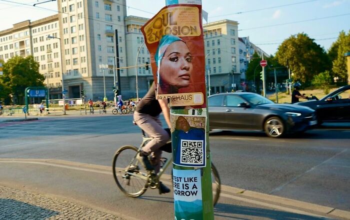 Cyclist perfectly aligned with a street poster, showcasing street photographer's talent for capturing perfect coincidences.