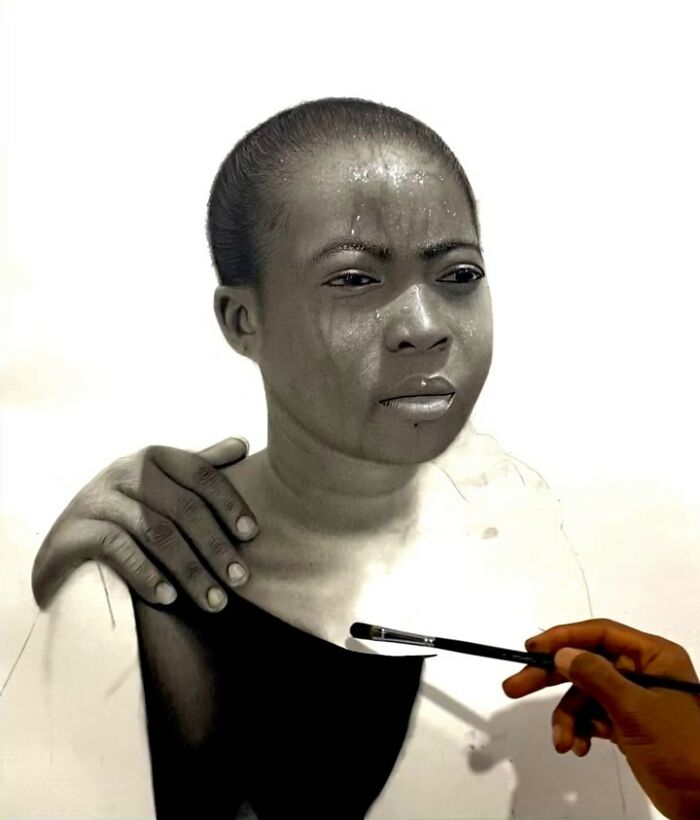 Artist applying paint to a hyperrealistic portrait showing detailed textures and lifelike facial features in progress.