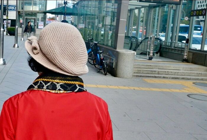 Street photographer captures perfect coincidences of a person in a red jacket and beige knitted hat in an urban setting.