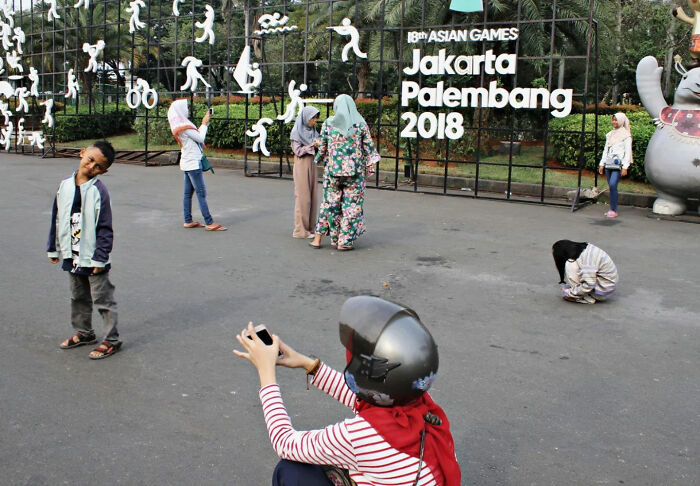 Photographer capturing perfectly timed street shots of people posing and interacting at an outdoor event in Jakarta.