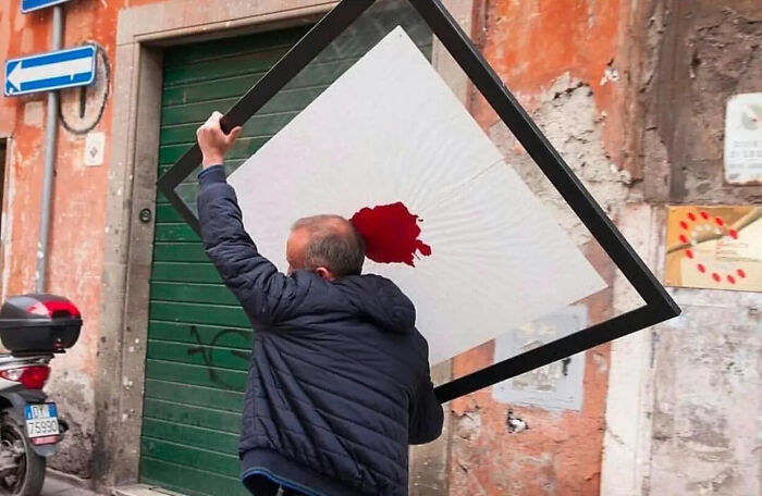 Man carrying large framed art on street, highlighting street photos capturing unexpected and beautiful moments in life.