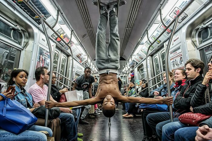 Candid street photo of a man doing a handstand in a subway train, capturing humanity and tender moments around the world.