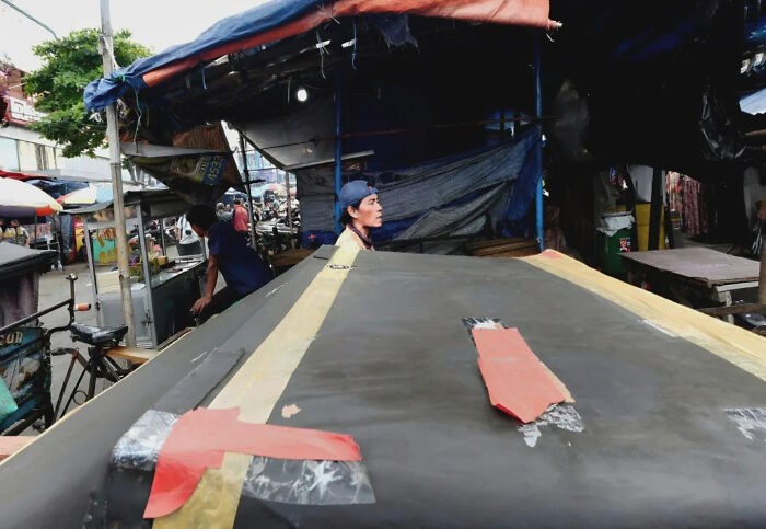 Street shot of two men under market tents with tarps, capturing perfectly timed urban life in a busy street setting.