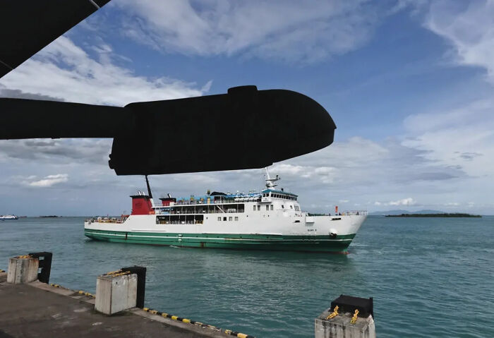 A perfectly timed street shot of a ship passing under a helicopter rotor, capturing an optical illusion effect.