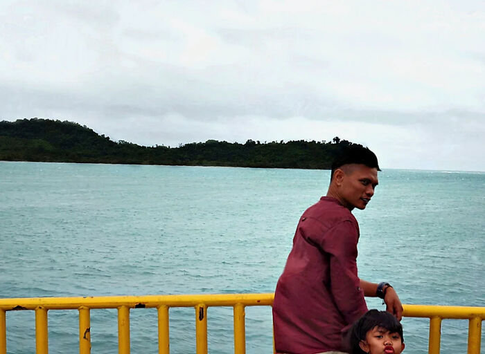 Two people by a yellow railing near water captured in a perfectly timed street shot by this photographer