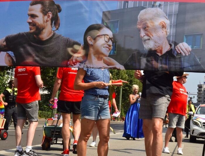 Street photographer capturing perfect coincidences with people and billboard images blending seamlessly on a city street.