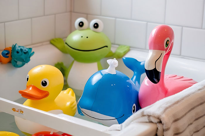 Bath toys (rubber duck, frog, whale, flamingo) lined in tub, reminding of hygiene mistakes adults overlook