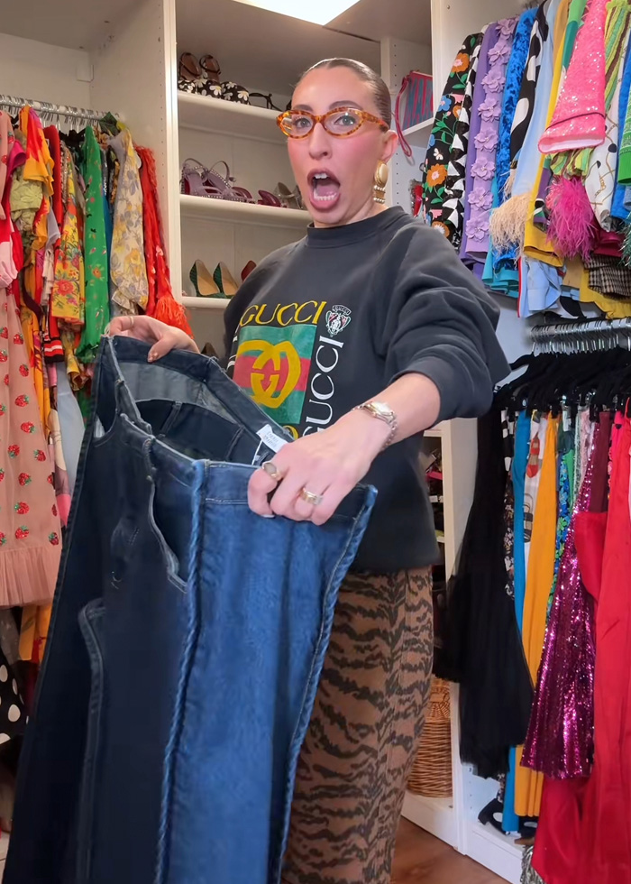 Influencer in colorful closet holding and showing new cubic jeans igniting social media debate on unique fashion trends.