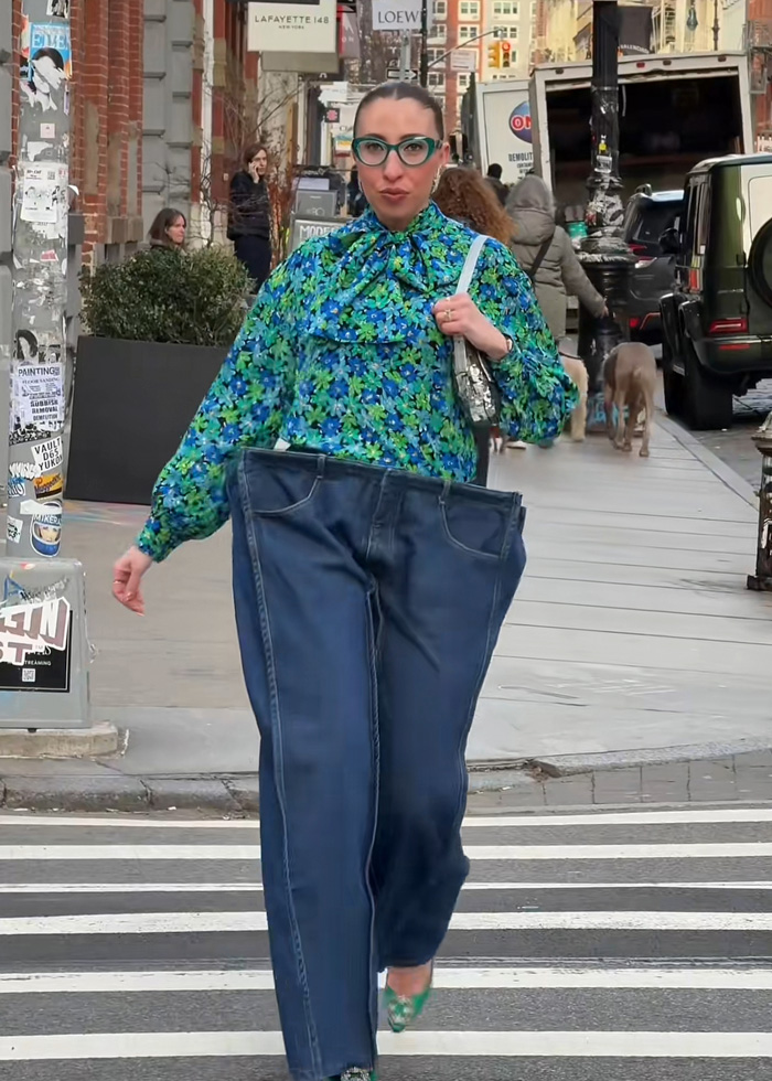 Woman wearing oversized cubic jeans and a vibrant floral blouse walking confidently on a city street.