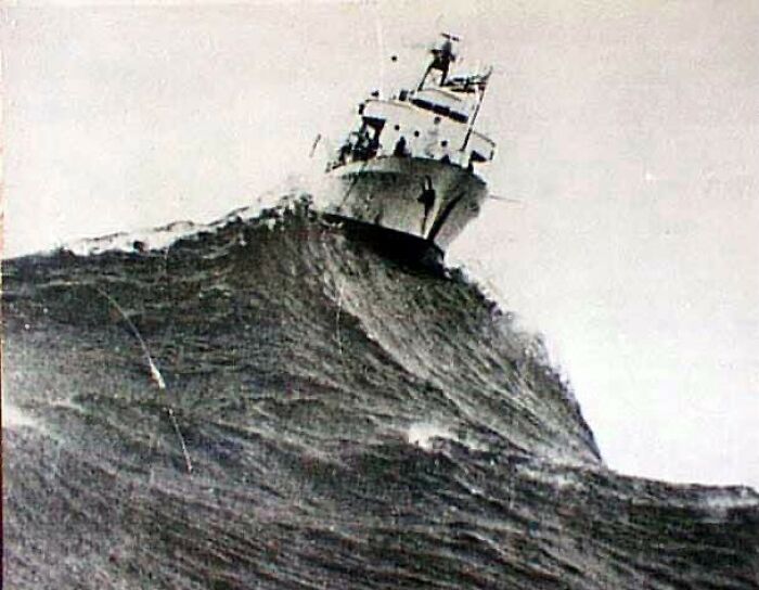 Ship struggling against massive ocean wave, capturing a dramatic moment in the history of humanity's maritime challenges.