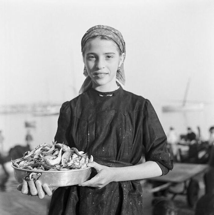 Young girl holding a bowl of freshly caught fish, capturing a sad and beautiful moment in the history of humanity.