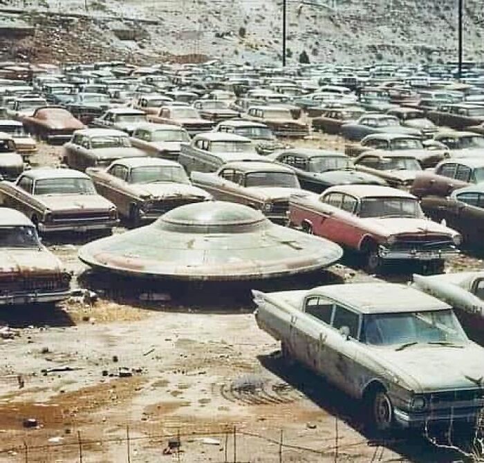 Vintage cars parked in a junkyard alongside a mysterious UFO, reflecting intriguing moments in the history of humanity.