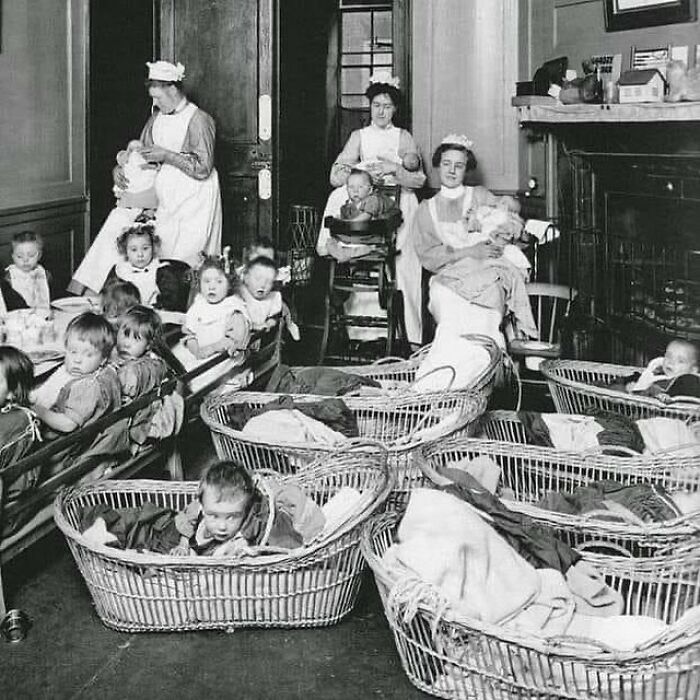 Historic black and white photograph of nurses caring for multiple infants in a crowded nursery, showing the history of humanity.