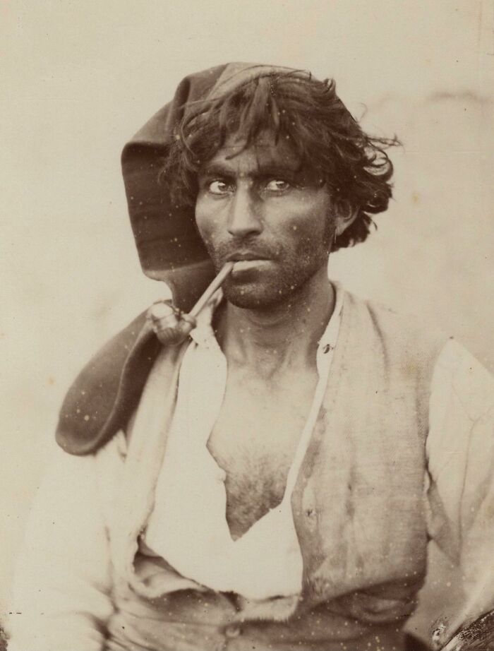 Vintage sepia photograph of a man smoking a pipe, capturing the sad and beautiful history of humanity.