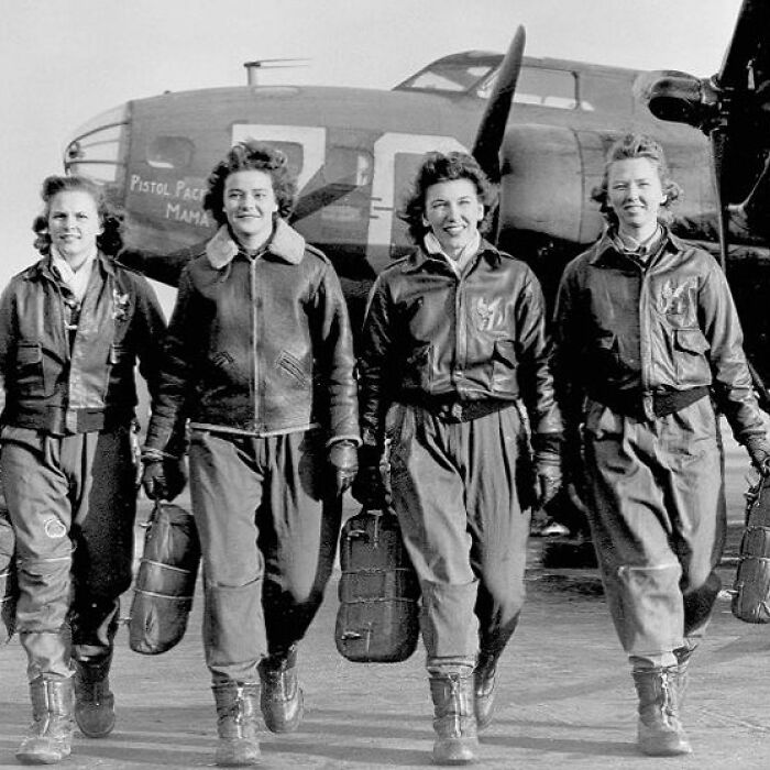 Four women pilots walking confidently in front of a military aircraft capturing history of humanity in a powerful photograph