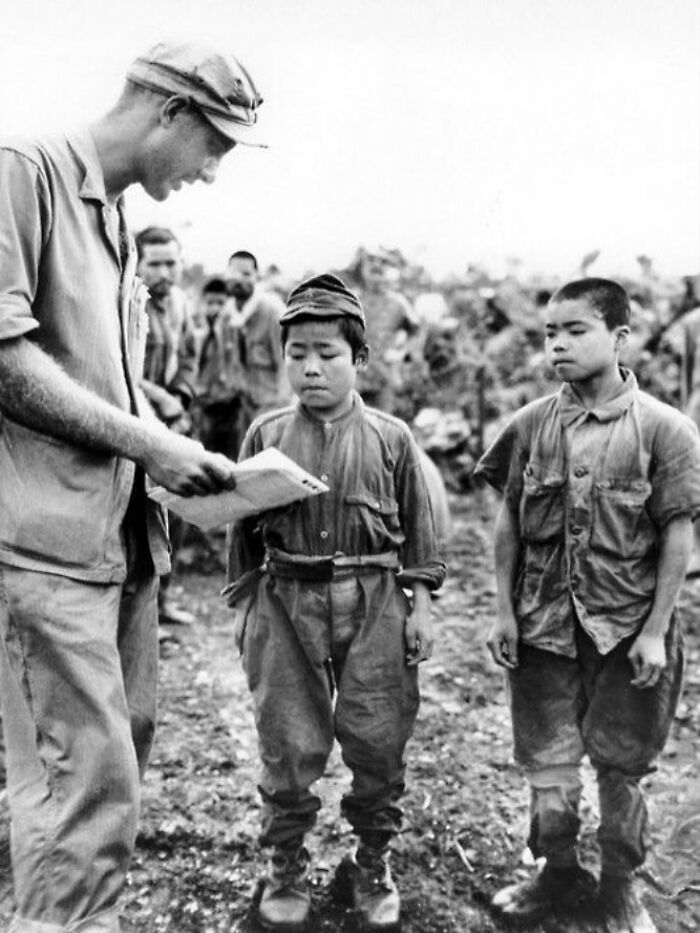 Black and white photograph showing young soldiers and a man reviewing documents, illustrating the history of humanity.