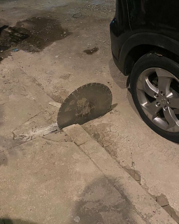 Circular saw blade embedded in the c*****d street pavement near a parked car, one of the weirdest things found in the streets.