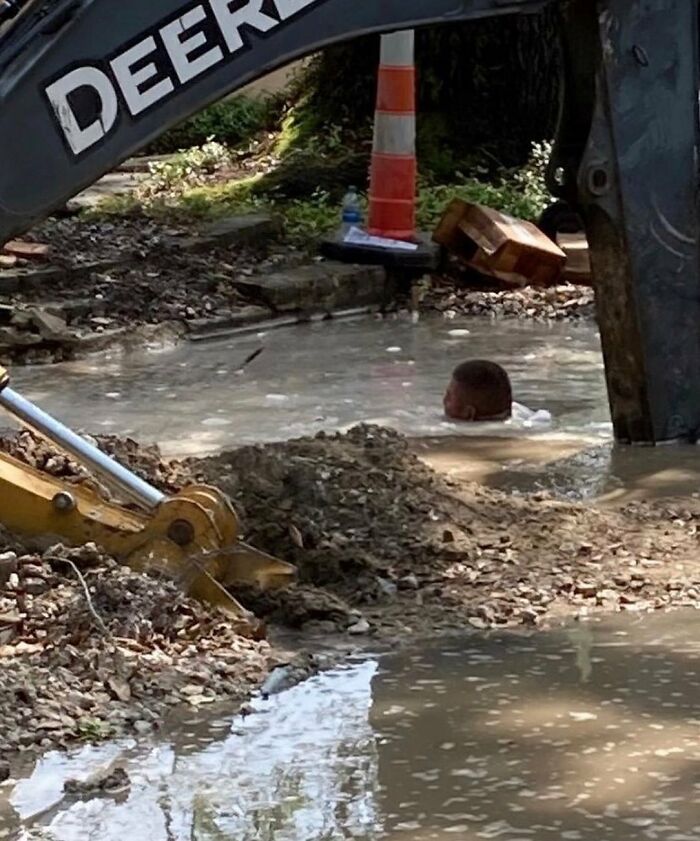 Construction site with a person submerged in muddy water, surrounded by machinery and debris, showcasing weird street finds.