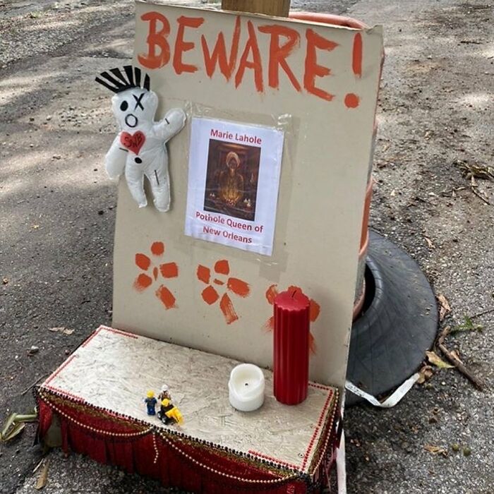Street altar with warning sign, candles, and voodoo doll as a weird thing found in the streets.