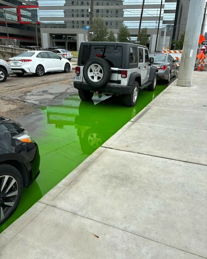 Jeep parked on a city street next to a bright green liquid puddle, showcasing one of the weirdest things found in the streets.
