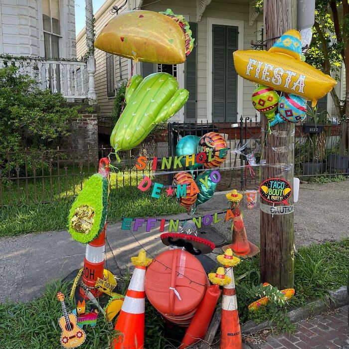 Colorful street installation with inflatable tacos, balloons, and traffic cones celebrating a Cinco de Mayo theme in an urban setting.