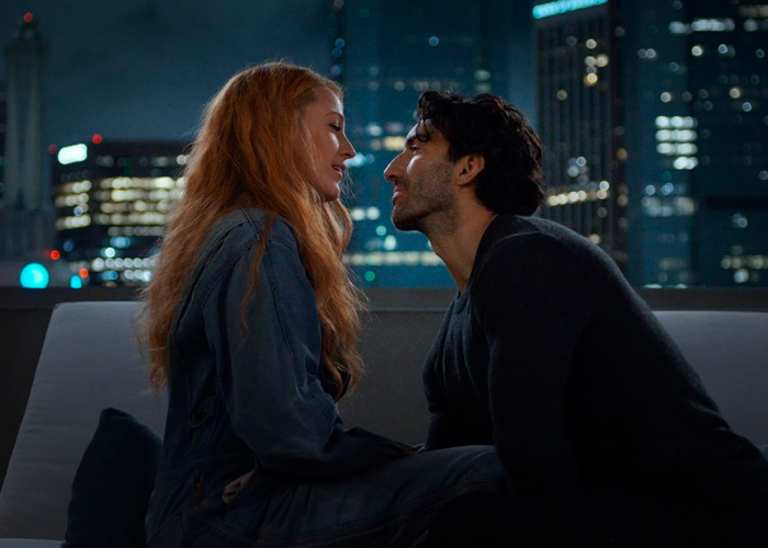 Couple sharing an intimate moment on a rooftop at night with city lights blurred in the background.