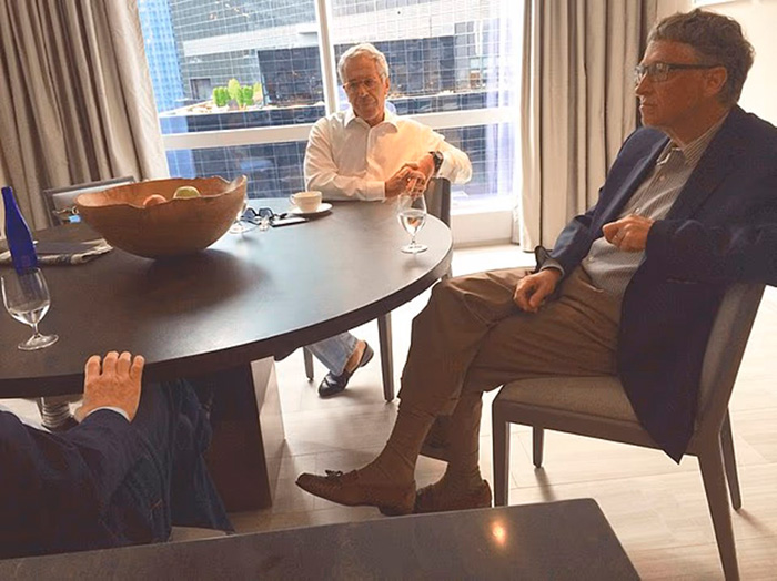 Bill Gates sitting in a suit at a round table during a meeting, related to Epstein files and secret antibiotics claim.