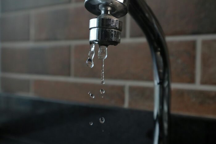 Close-up of a leaking faucet with water drops falling, illustrating common shipping containers maintenance problems.