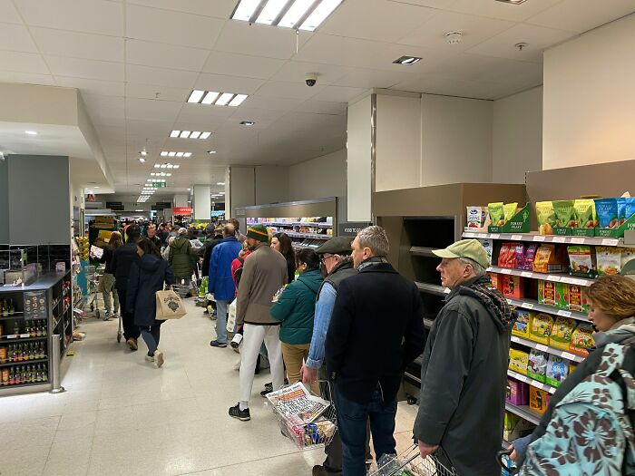 Shoppers in a crowded supermarket aisle standing in line illustrating how far from reality rich people can be.