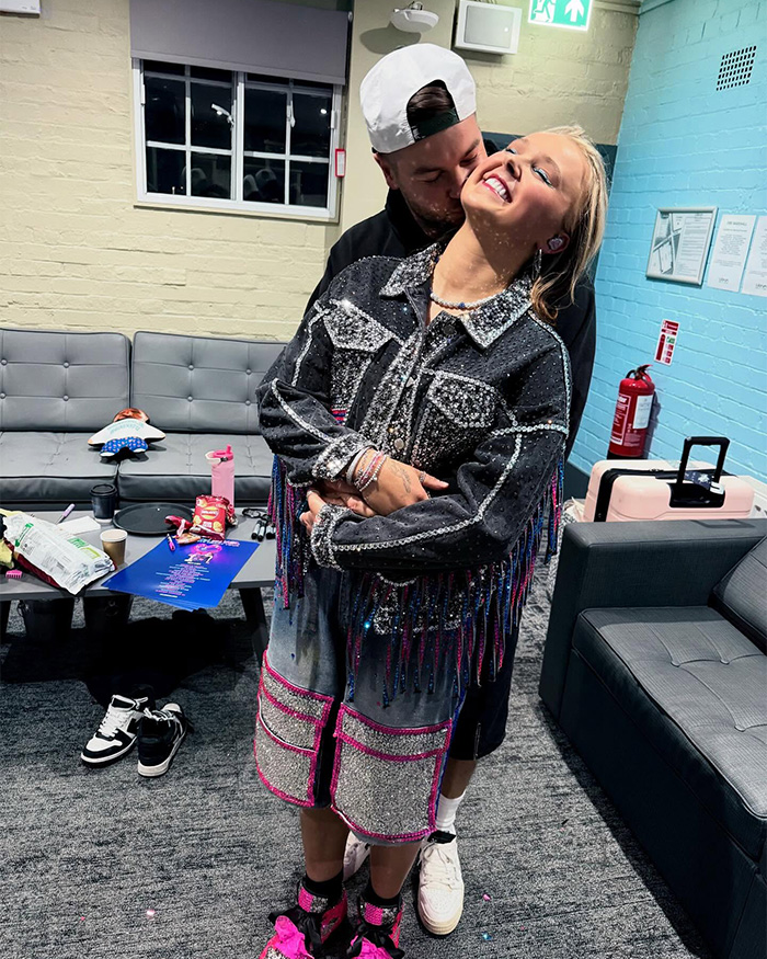 JoJo Siwa smiling and hugging a man backstage, showcasing her dramatic transformation and new name change after bizarre adventure.