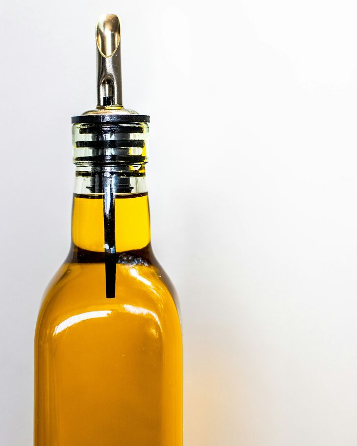 Glass bottle filled with oil and a metal pour spout, symbolizing petty fights over Christmas couples.