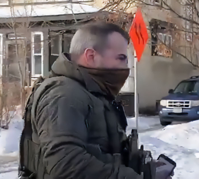 Father of ICE agent pictured outside a residential area wearing tactical gear and a face covering during winter.