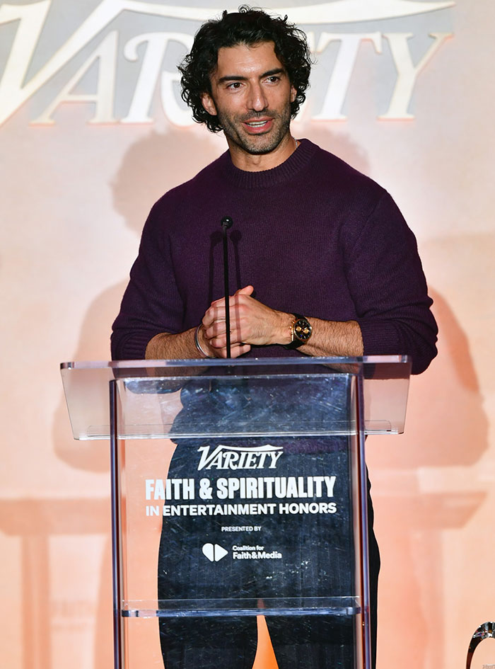 Man with curly hair in a purple sweater speaking at a Variety Faith and Spirituality in Entertainment Honors event podium.